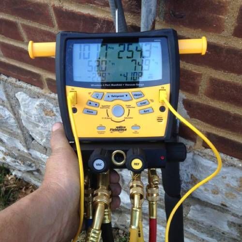 A hand is holding a yellow and black device that shows a temperature of 25.4 degrees