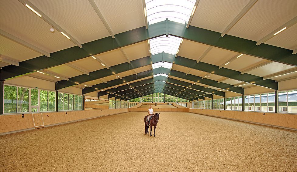 Leere Reithalle mit Sandboden, Holzwänden und schrägen Dachbalken