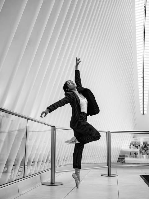 Ballerina in business suit dances by modern architecture; black and white. At the Oculus, NYC.