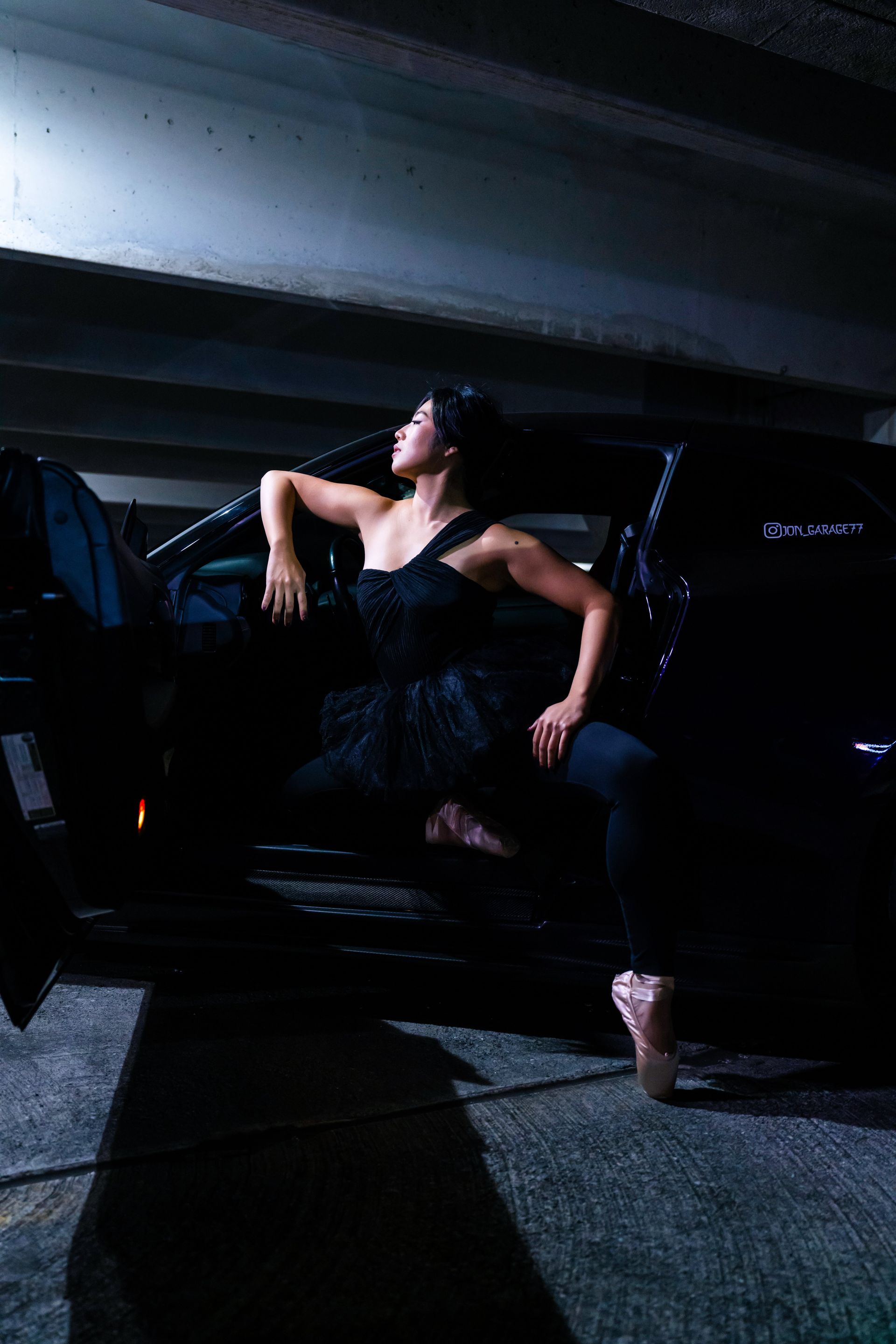 Minnie Lee performing a ballet pose beside a sports car