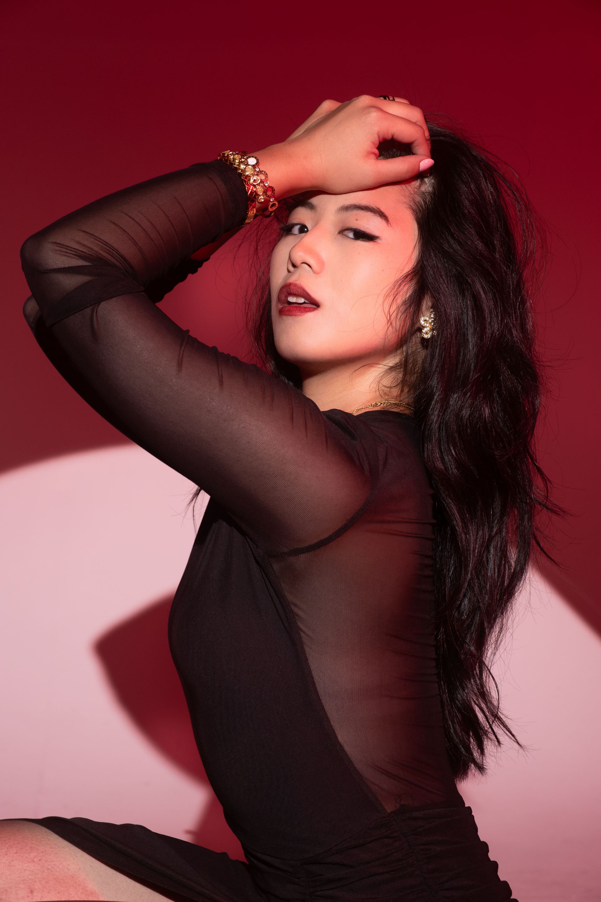 Luxury editorial portrait in controlled red studio light, disciplined posture and sculptural lines, model Minnie Lee.