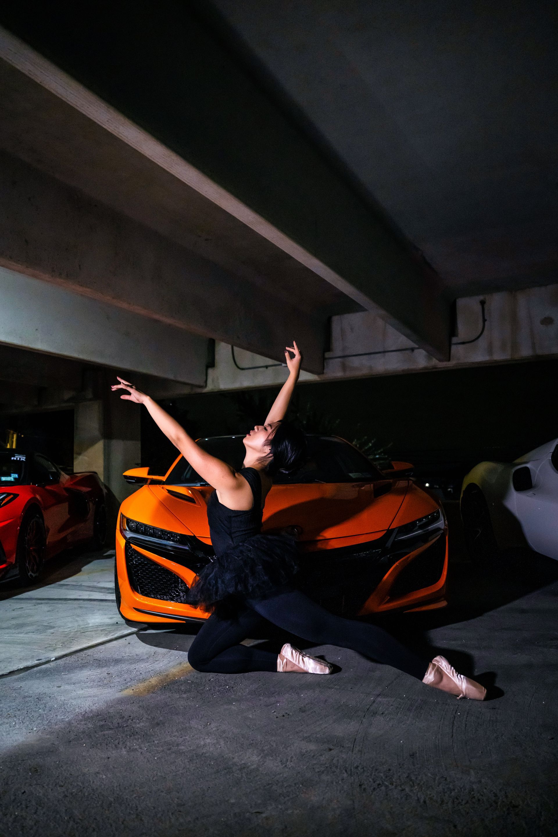 Minnie Lee performing a ballet pose beside a sports car