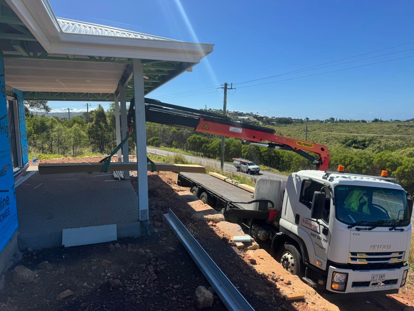 Construction Truck with Crane Lifting a Load Near a Building Site, Sunny Day — J & M Transport Plus in Rockhampton, QLD