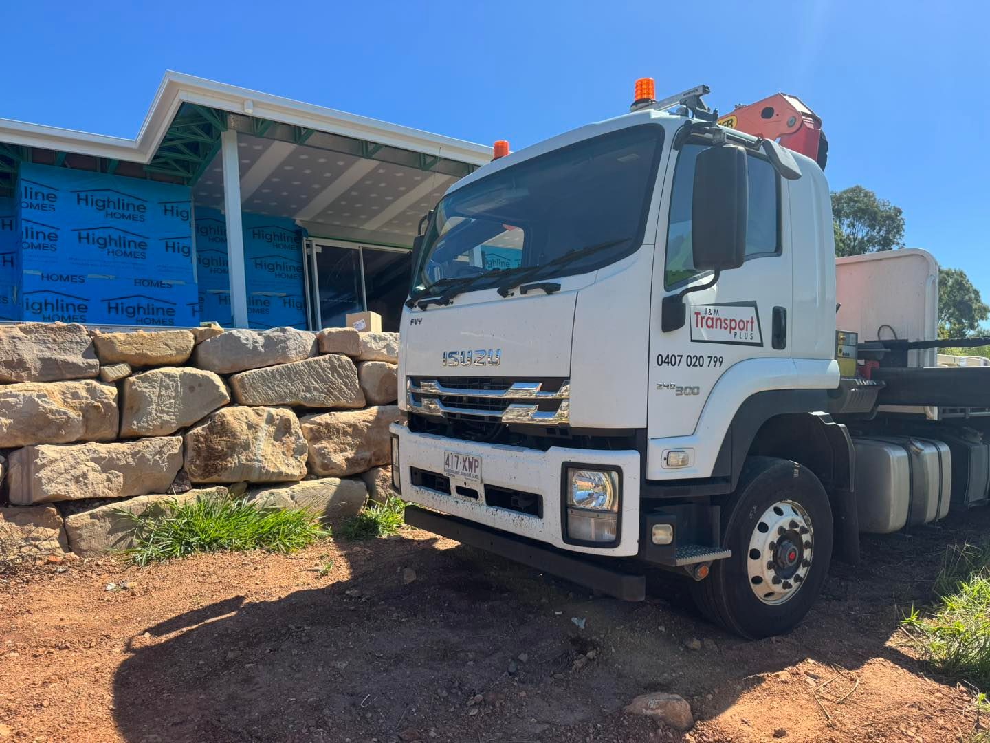 White Work Truck Parked Near a Stone Wall and Building Under Construction — J & M Transport Plus in Barmaryee, QLD