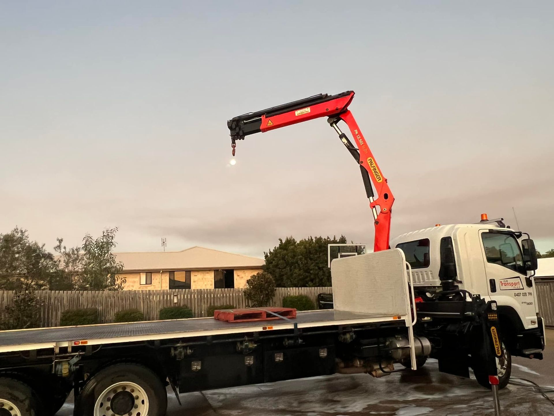 Red Crane Extending from A White Flatbed Truck — J & M Transport Plus in Barmaryee, QLD