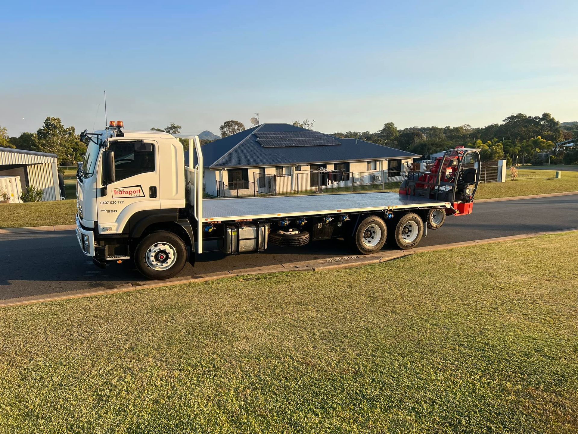 White Flatbed Truck on Road, Grassy Lawn in Foreground — J & M Transport Plus in Barmaryee, QLD