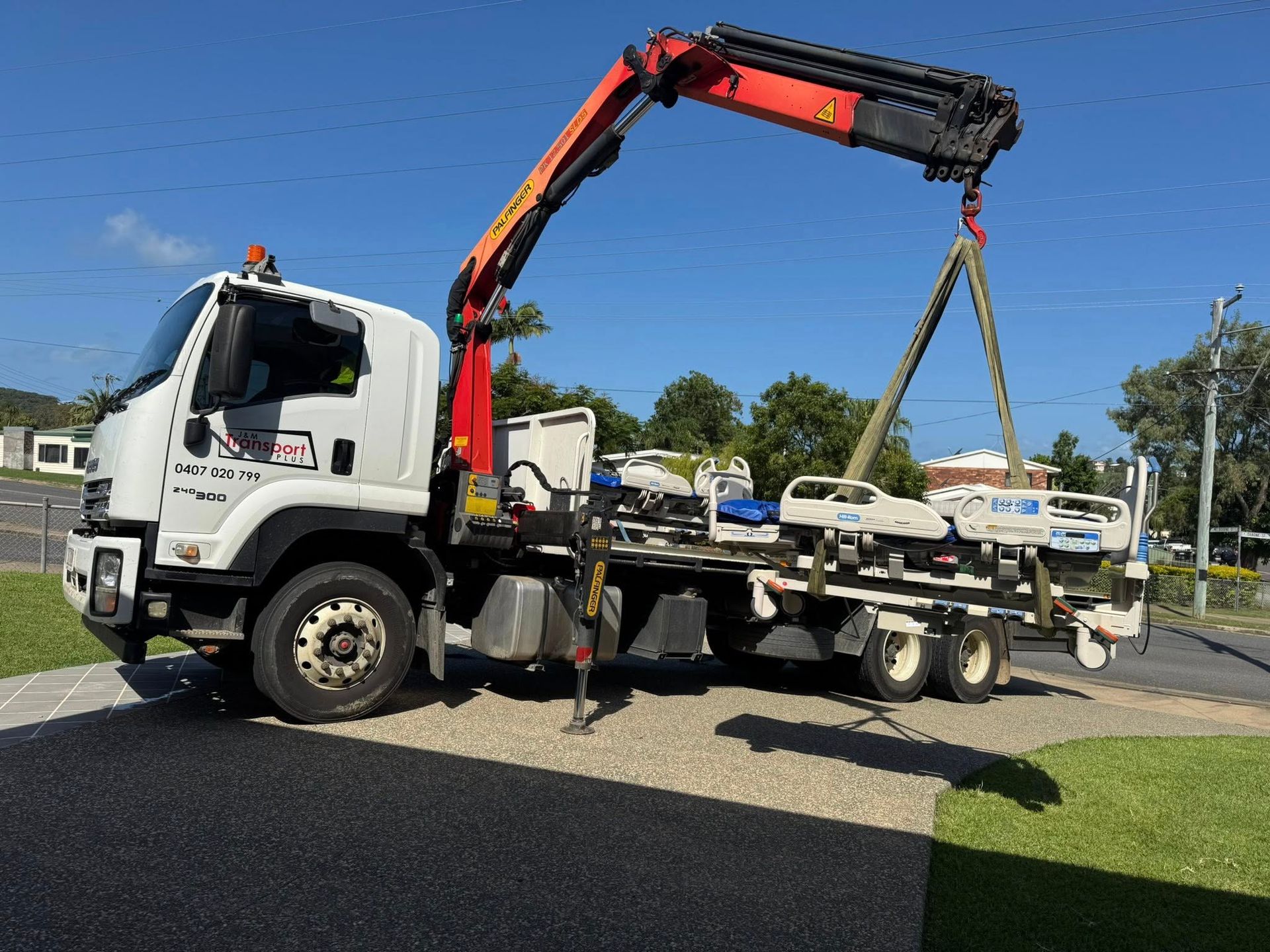 A White Truck with A Crane Lifting Medical Beds. Bright Sunny Day, Outdoors — J & M Transport Plus in Barmaryee, QLD