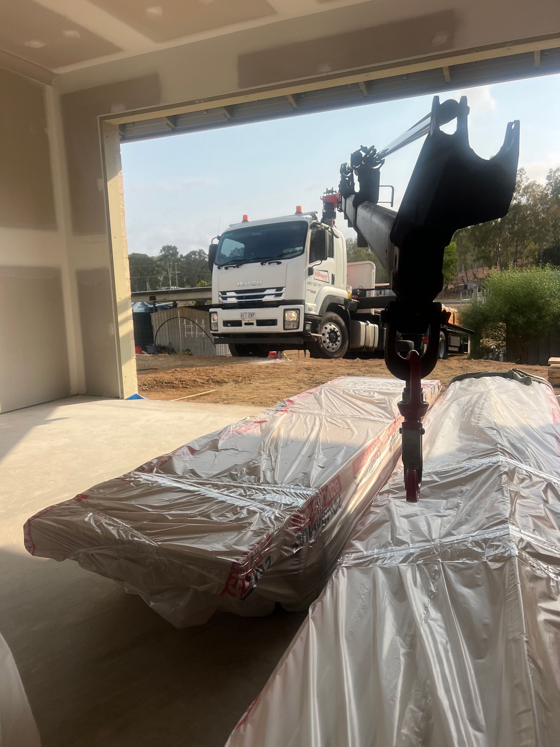 Wrapped machinery in a garage, with a crane truck visible outside.