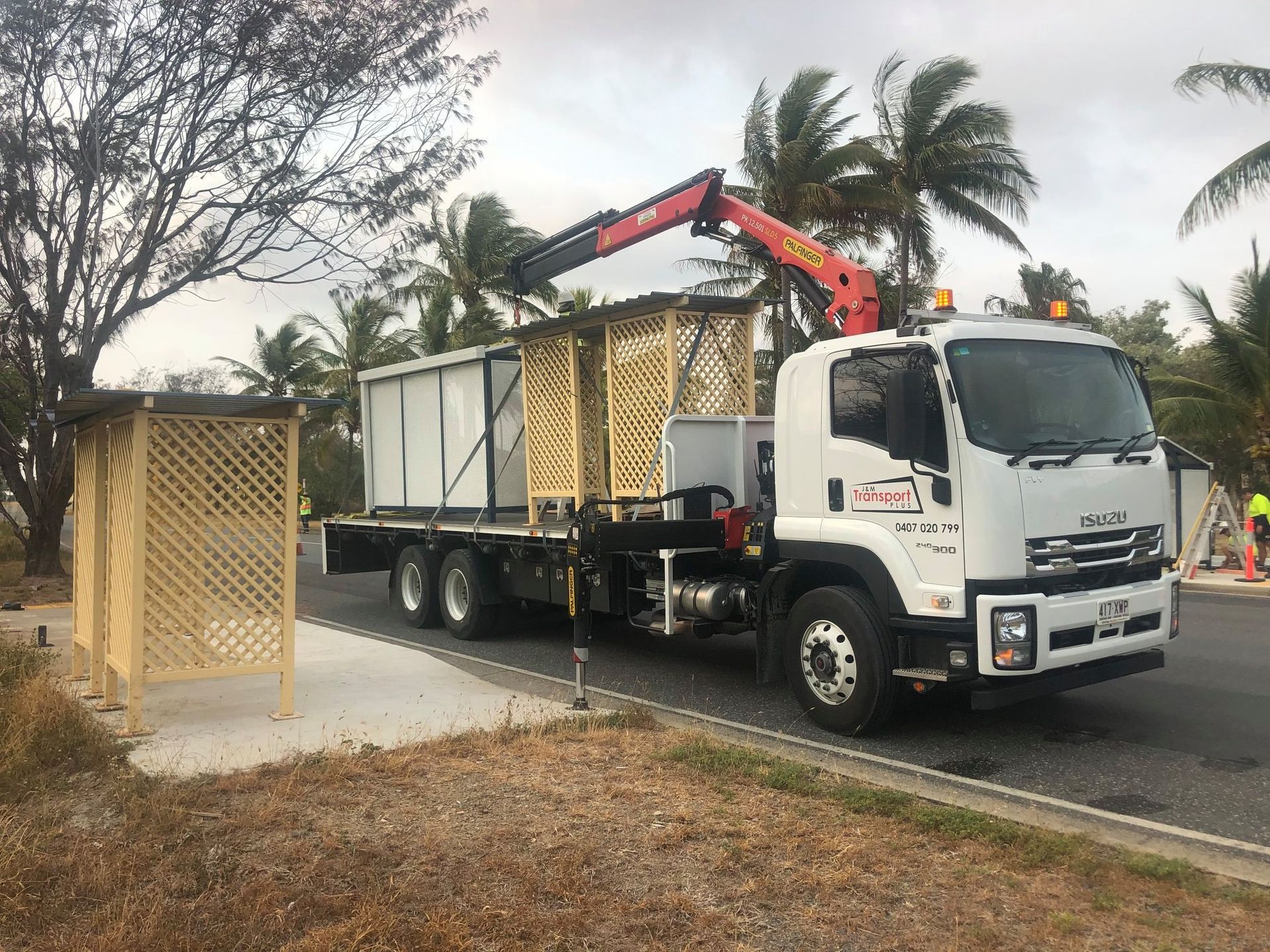 A Truck with A Crane Loading a Wooden Structure Near a Curb — J & M Transport Plus in Barmaryee, QLD