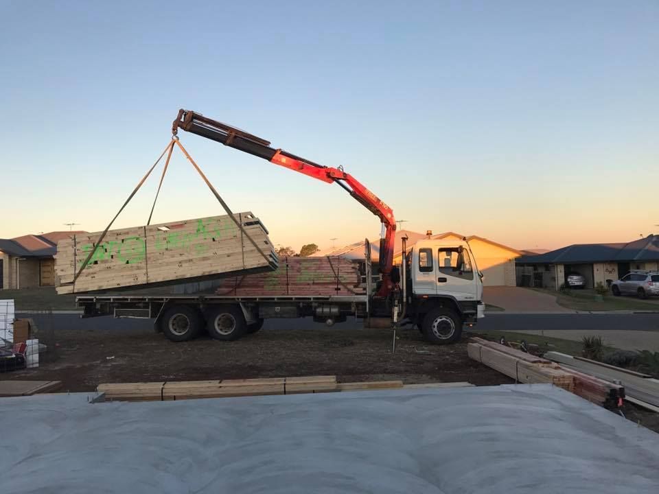 A Crane Truck Unloading Lumber at A Construction Site in A Residential Area — J & M Transport Plus in Barmaryee, QLD