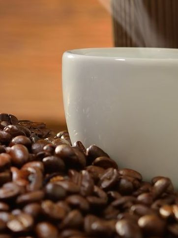 Close-up of a man and woman clinking a white coffee cup in a coffee shop