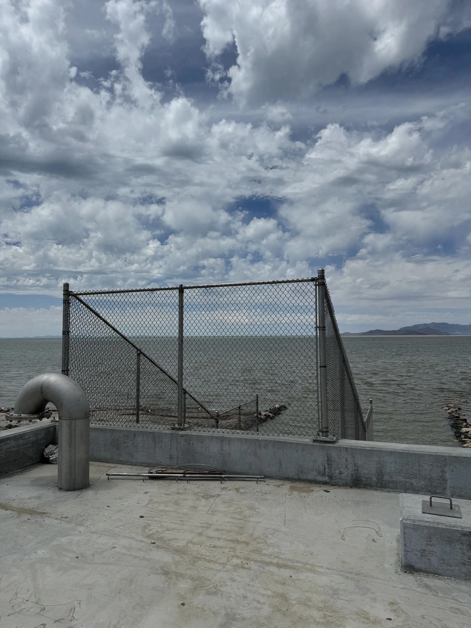 Fishing net on a concrete pier overlooking rough water under a cloudy sky