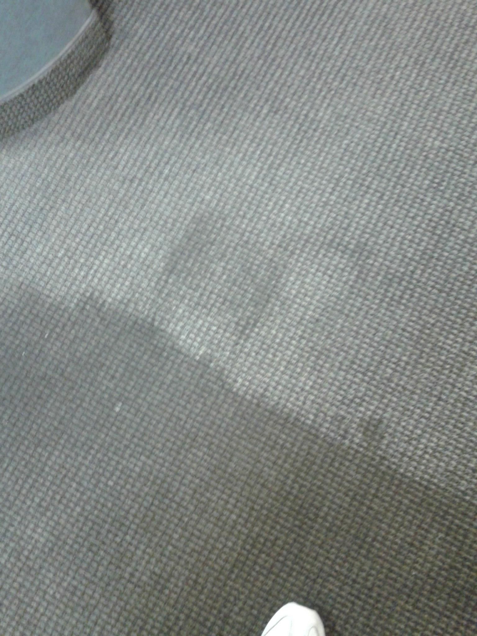 A person is standing on a dirty carpeted floor.