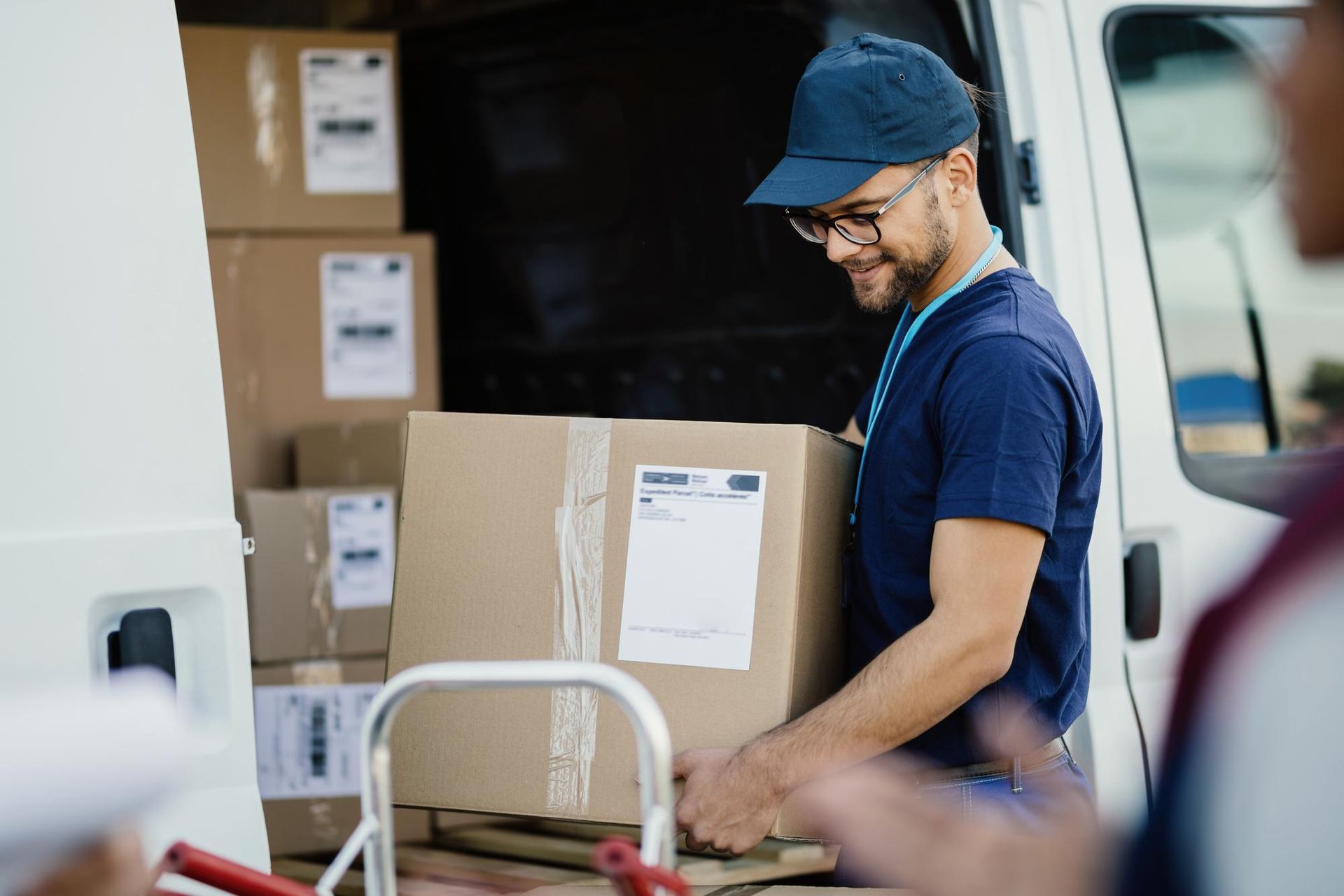 Delivery worker loading cardboard boxes into a van