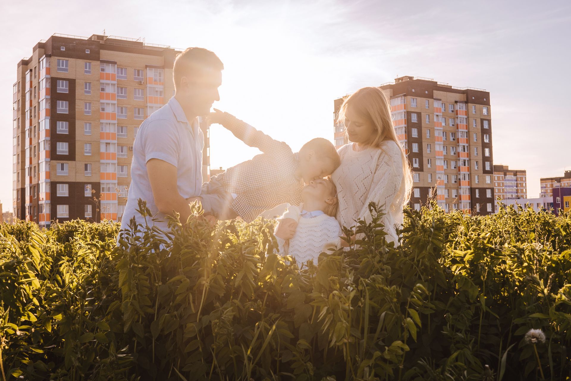 Family in a sunlit field with apartment buildings in the background