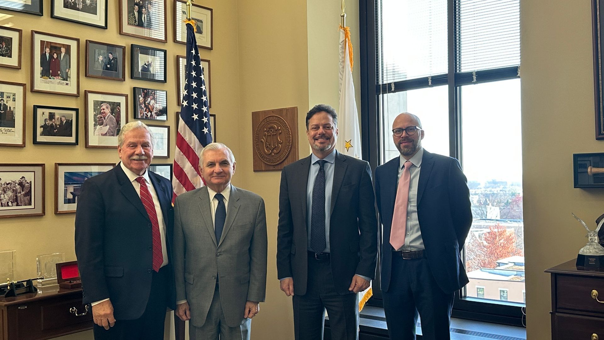A group of men in suits and ties are posing for a picture in a room.