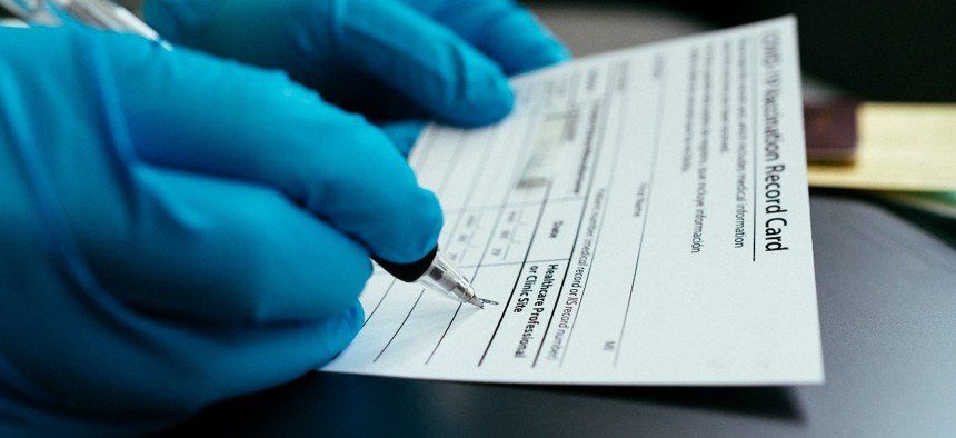 A person wearing blue gloves is writing on a piece of paper with a pen.