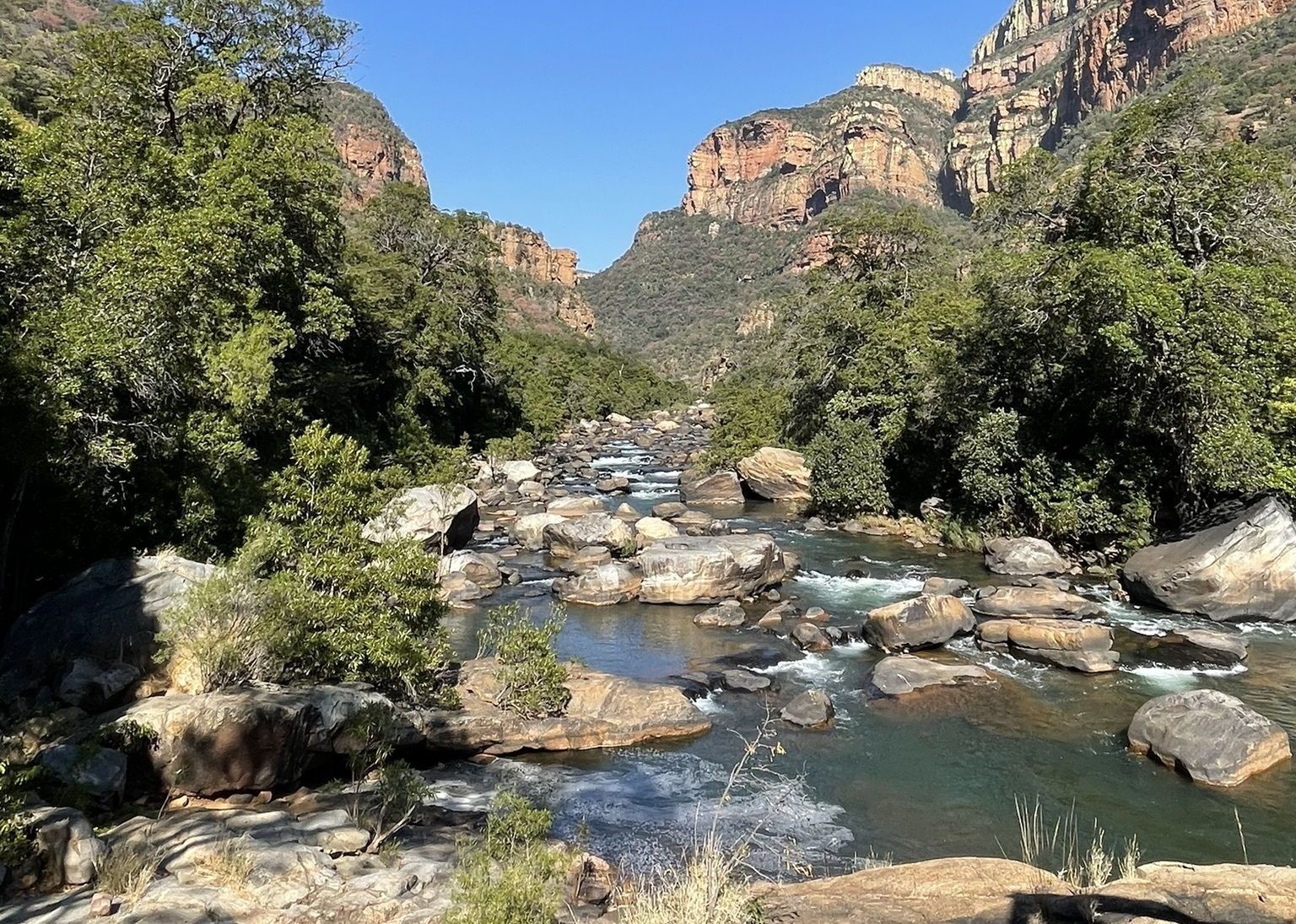 a river flowing through a valley surrounded by trees and rocks .