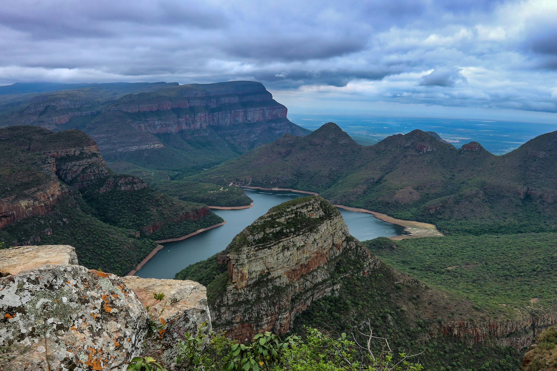 a view of a river surrounded by mountains on a cloudy day