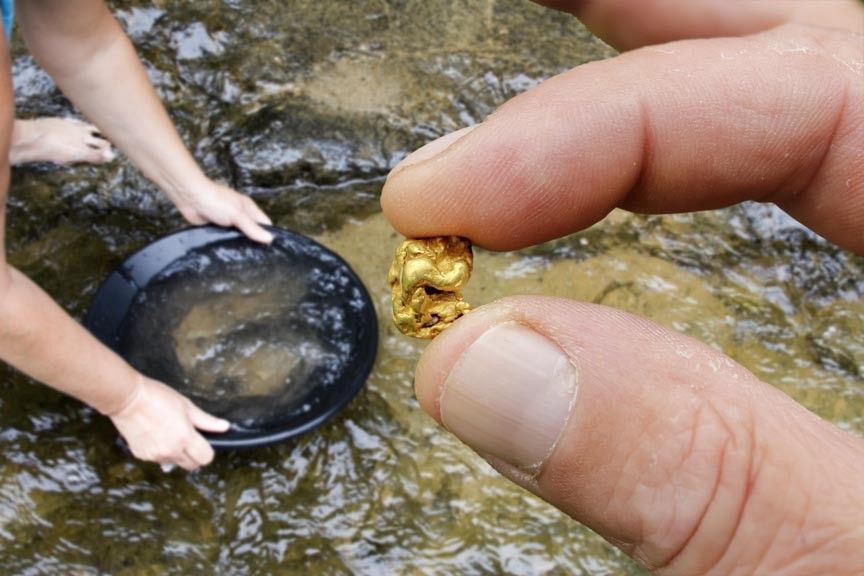 A person is holding a small piece of gold in their hand.