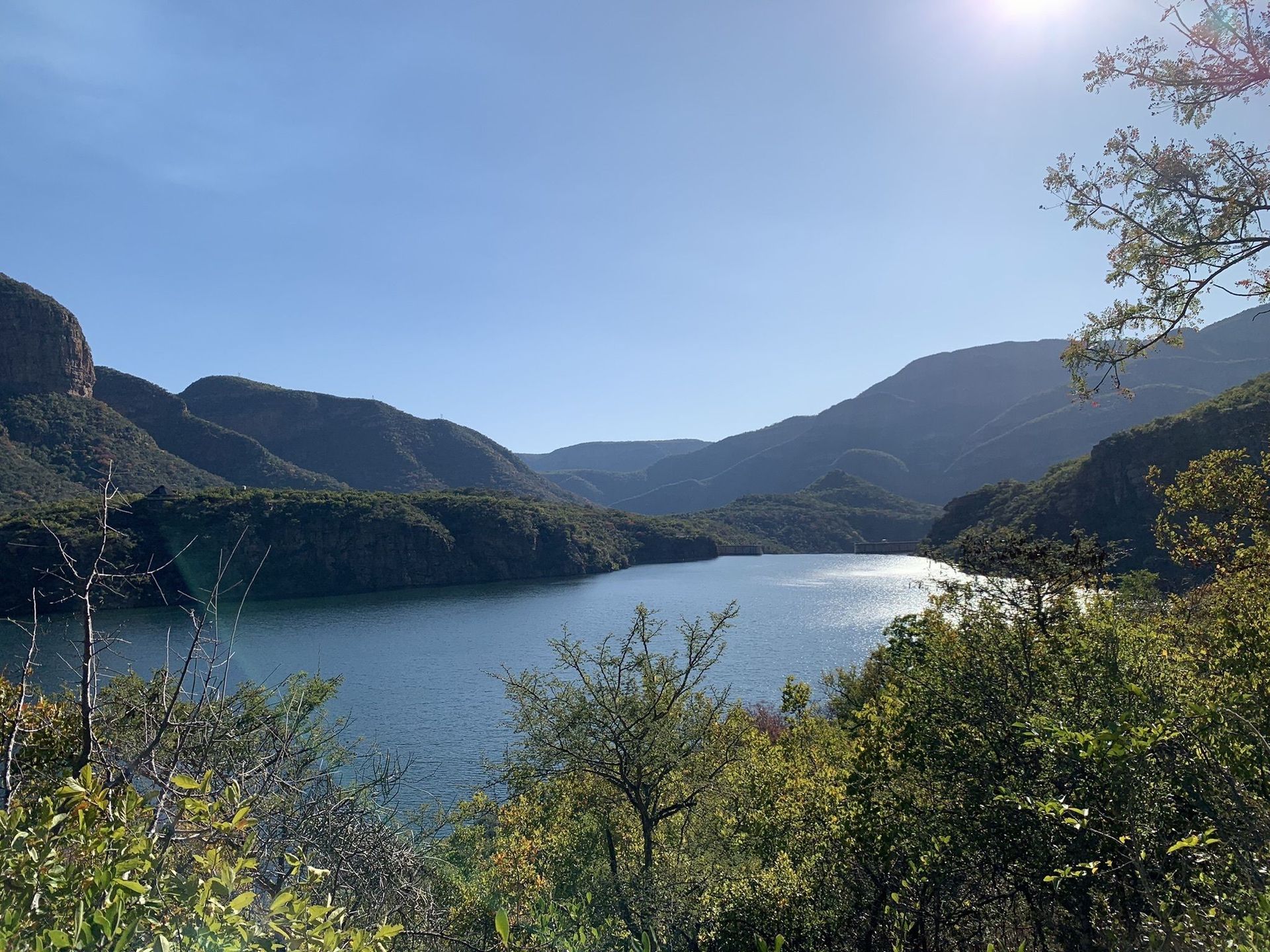 a lake surrounded by mountains and trees on a sunny day