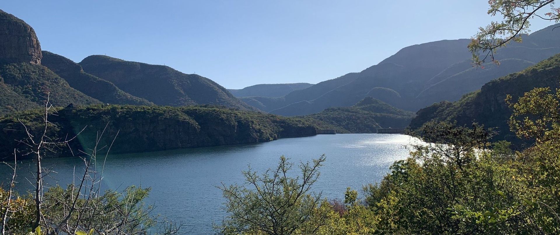 a lake surrounded by mountains and trees on a sunny day
