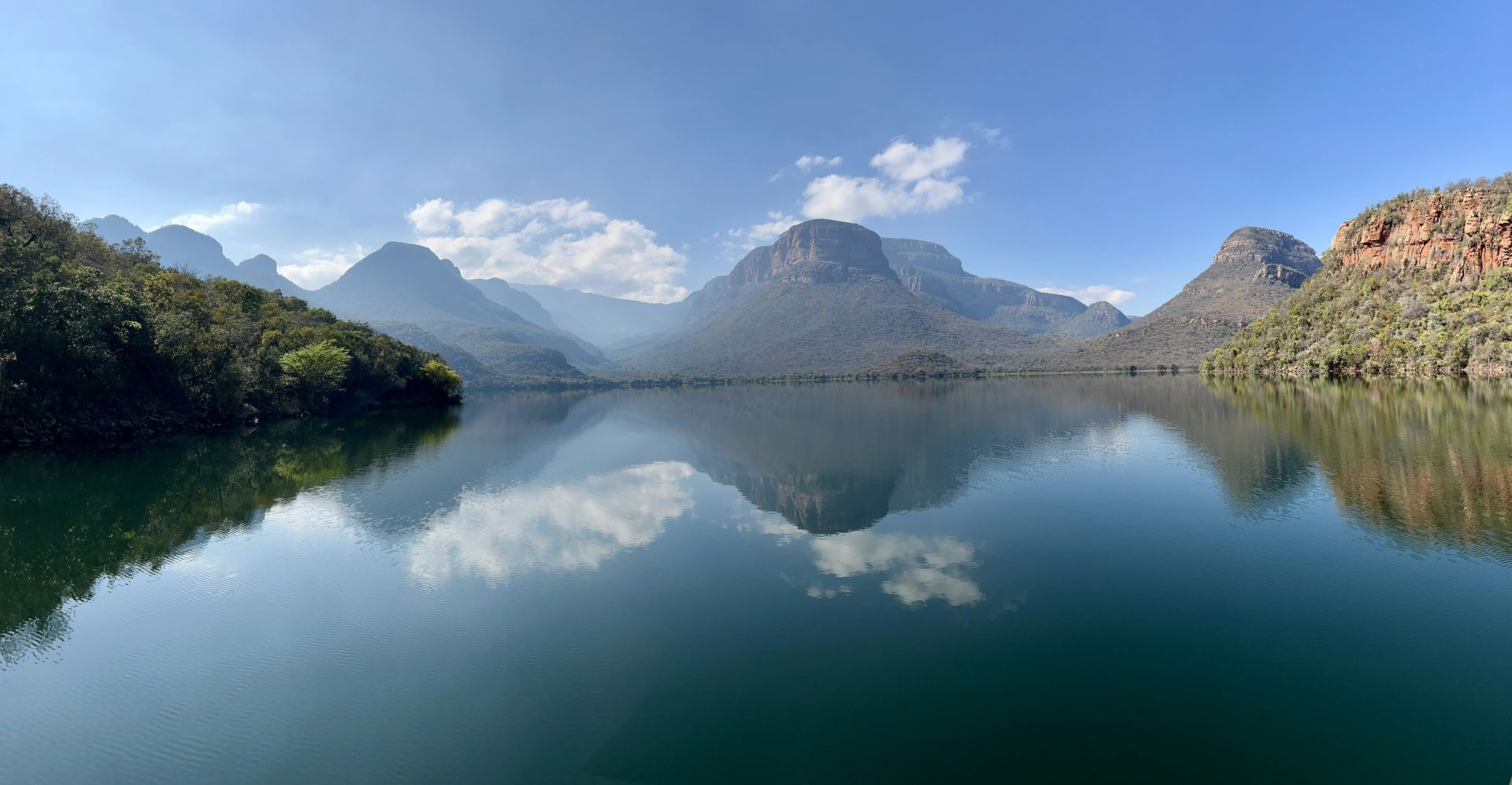 A lake with mountains in the background and trees on the shore.