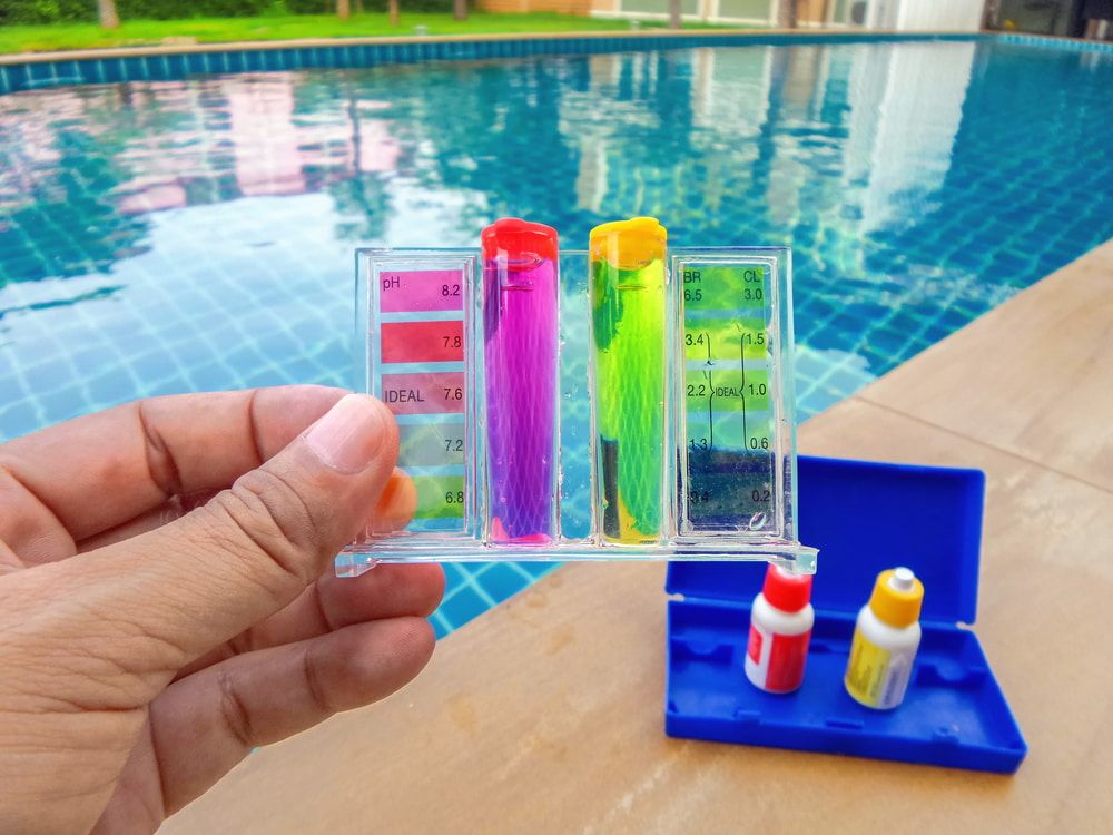 A person is holding a test tube in front of a swimming pool. — Cooloola Coast Property Maintenance in Rainbow Beach, QLD