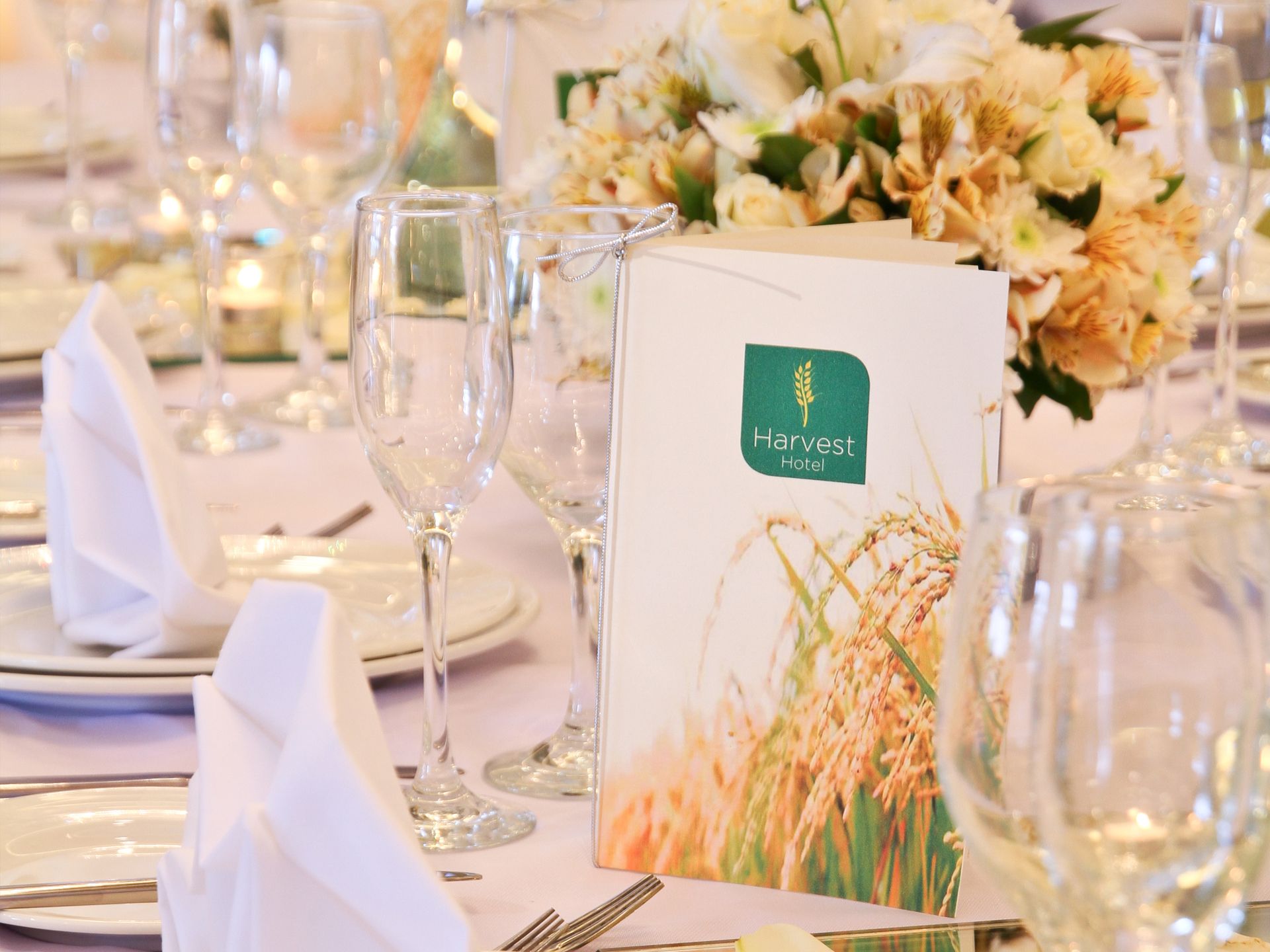 A table with plates , glasses , and a menu on it at an event hall for wedding in Nueva Ecija hotel
