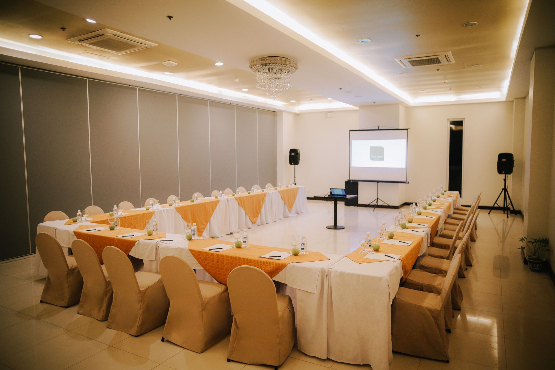 U-shaped table seating arrangement in a conference room with chairs, yellow table runners, and a projection screen.