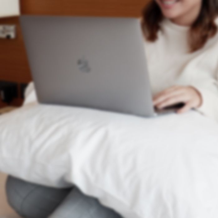 Woman in white sweater using laptop on bed at Harvest Hotel Cabanatuan