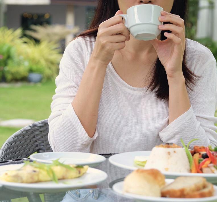 Woman sipping coffee at outdoor breakfast table, Harvest Hotel Cafe Ecija