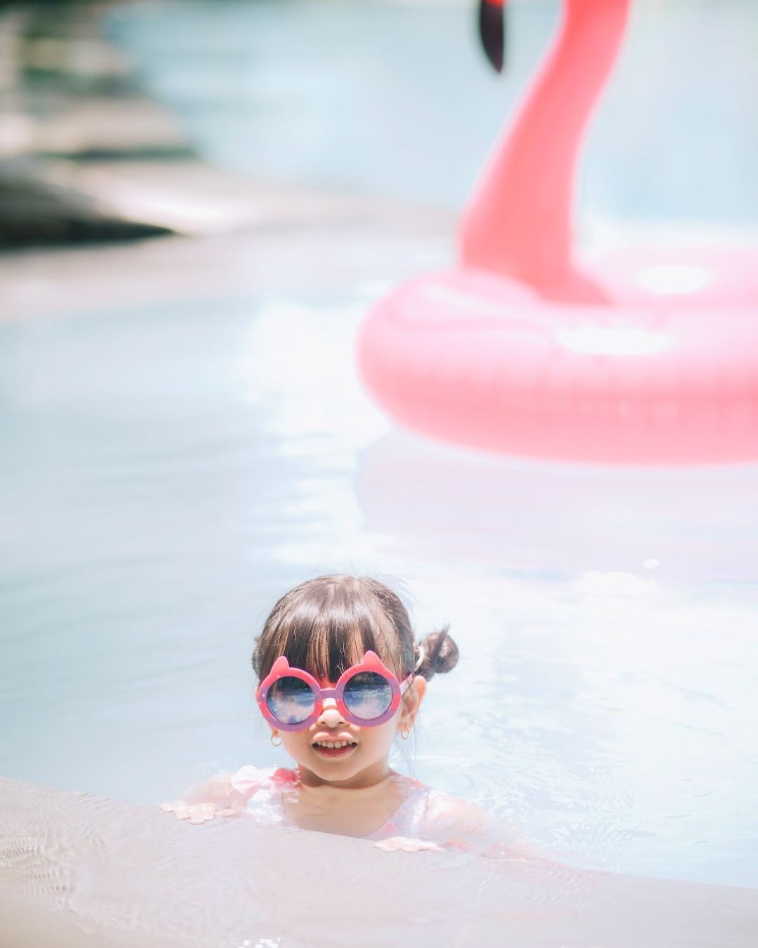 Happy child swimming in Harvest Hotel pool with flamingo float