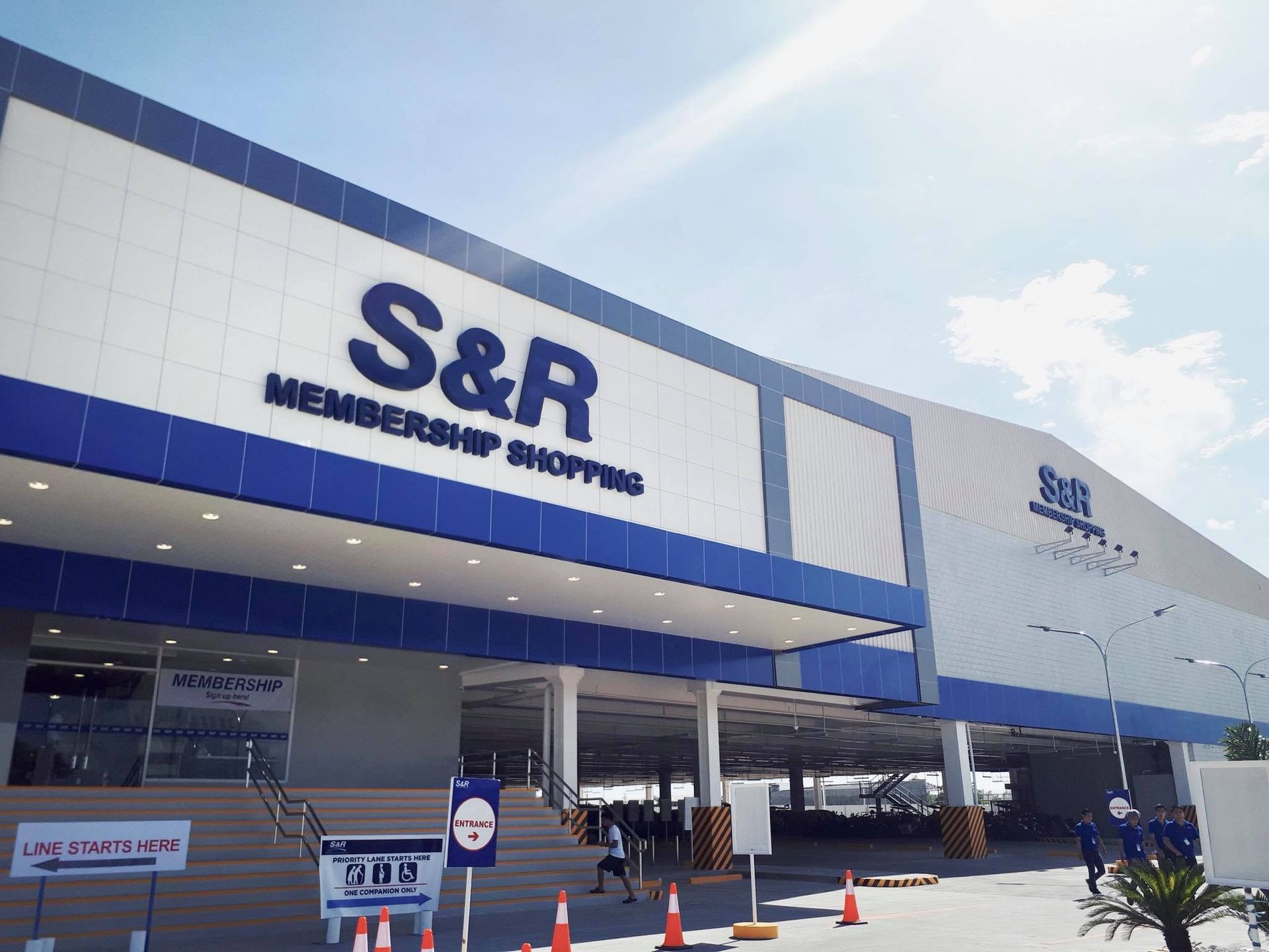 S&R Membership Shopping store exterior with blue and white facade. Entrance with stairs and people.