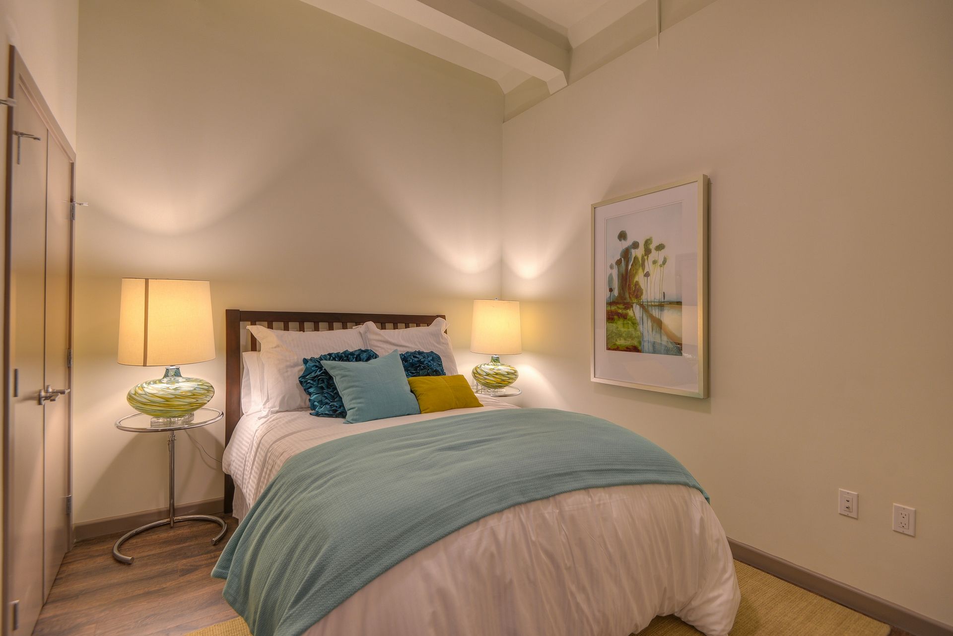 Cozy bedroom with a bed, bedside lamps, teal bedding, and framed wall art