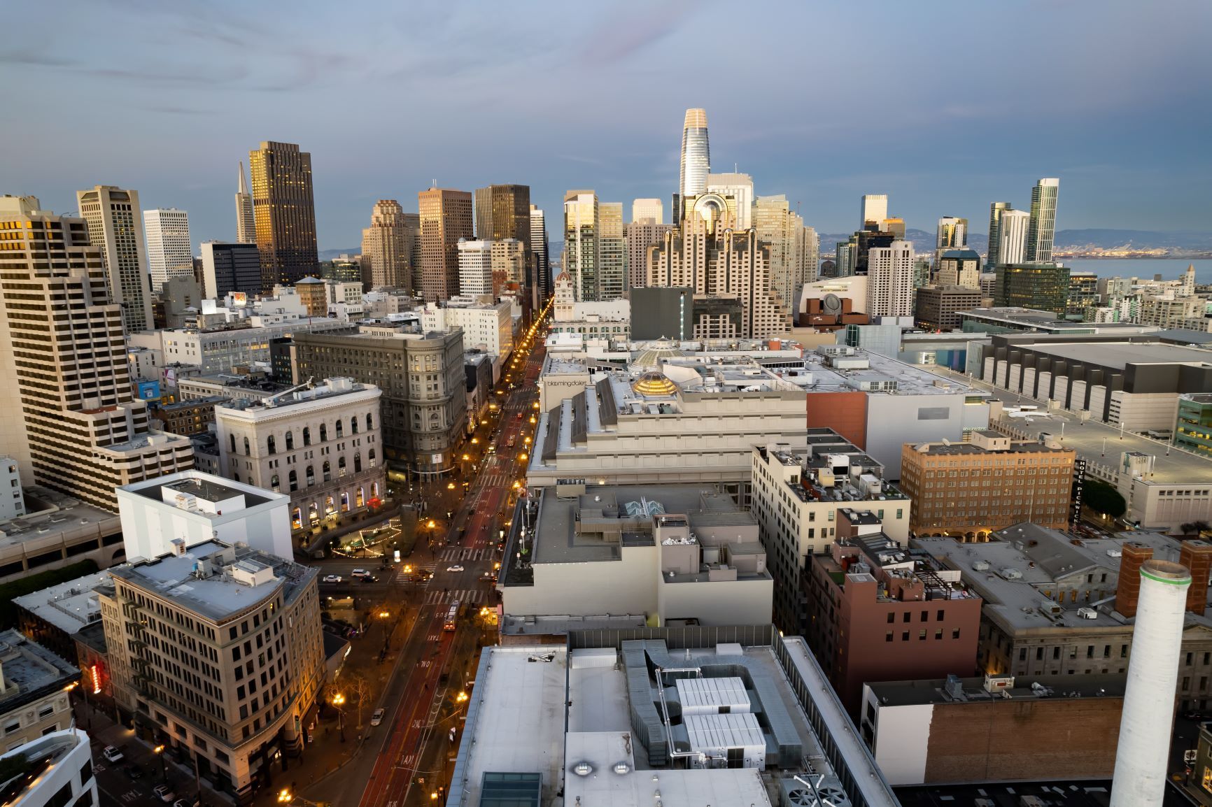 City skyline at sunset with a busy lit street running through downtown buildings