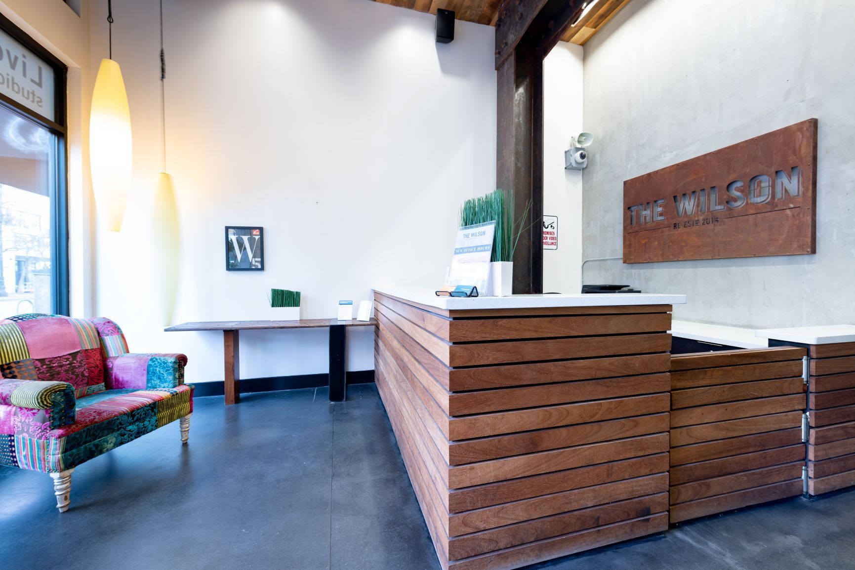 Bright lobby with wooden reception desk, colorful chair, and wall sign reading “WILSON”