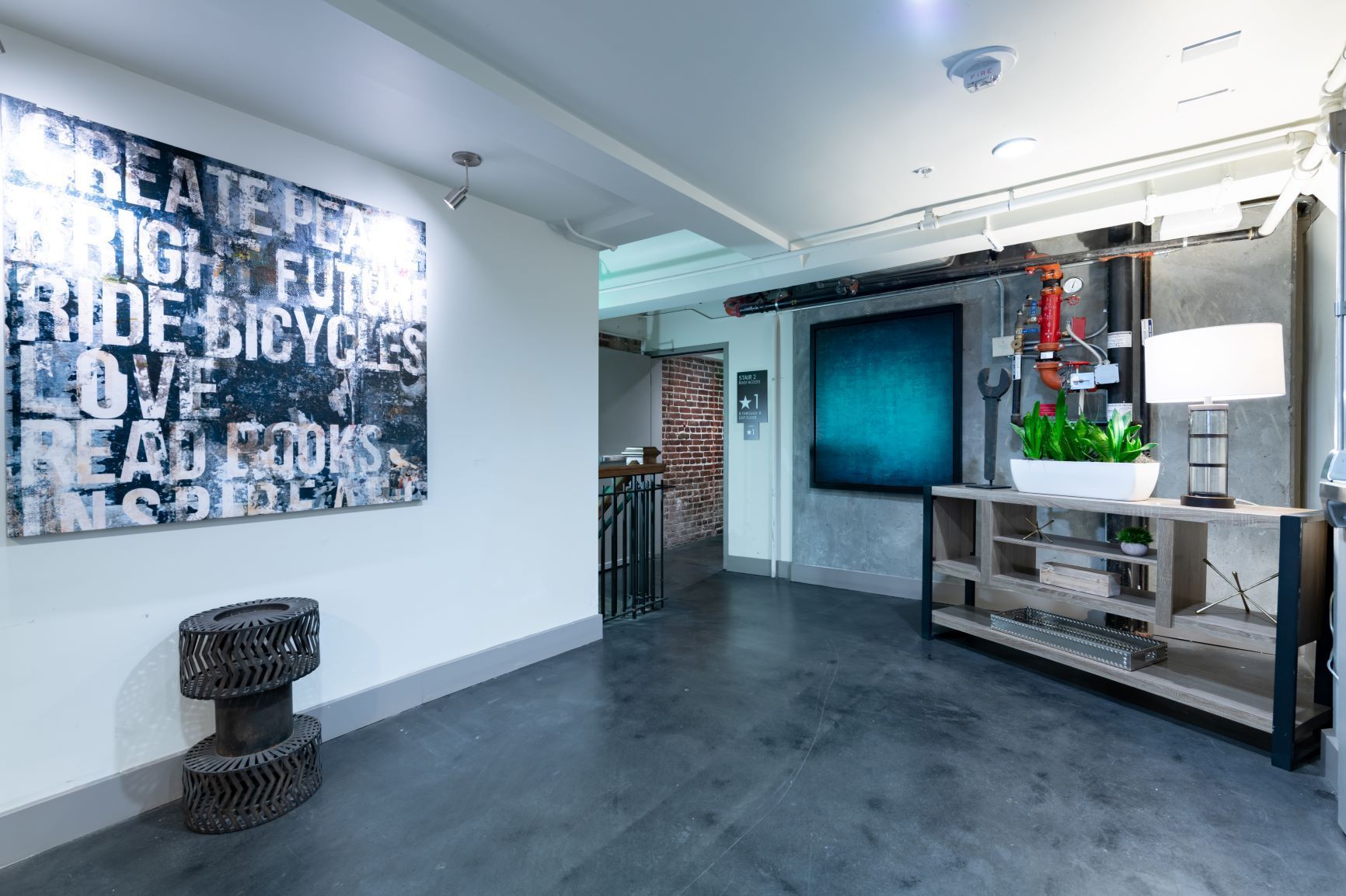 Modern office lobby with large wall art, dark floor, and a metal-framed reception area