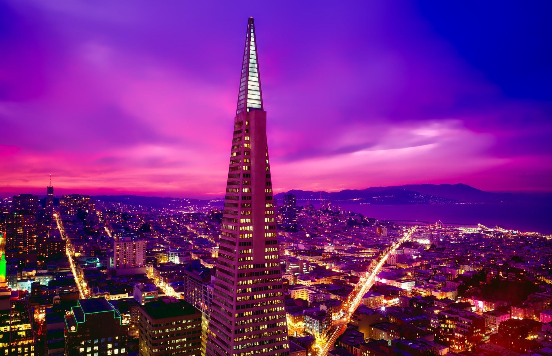 San Francisco skyline at sunset with the illuminated Transamerica Pyramid under a vivid purple sky
