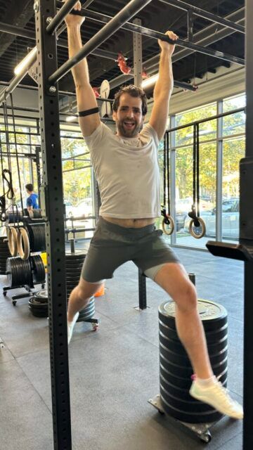 Salzy giving his best  A member hanging from the pull-up bar, smiling as he hangs.