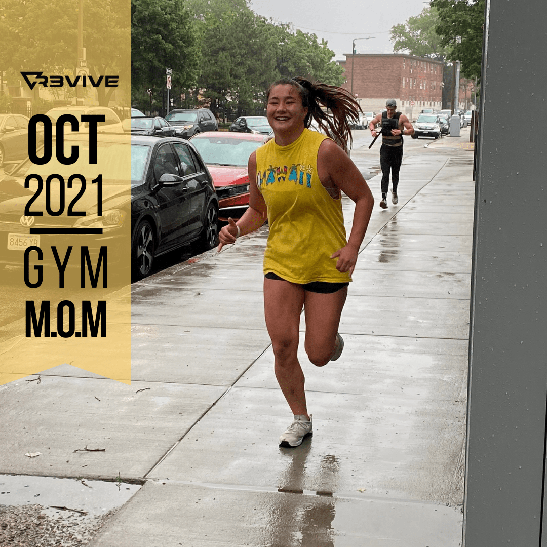 Woman running in the rain on a sidewalk wearing a yellow tank top and shorts.  