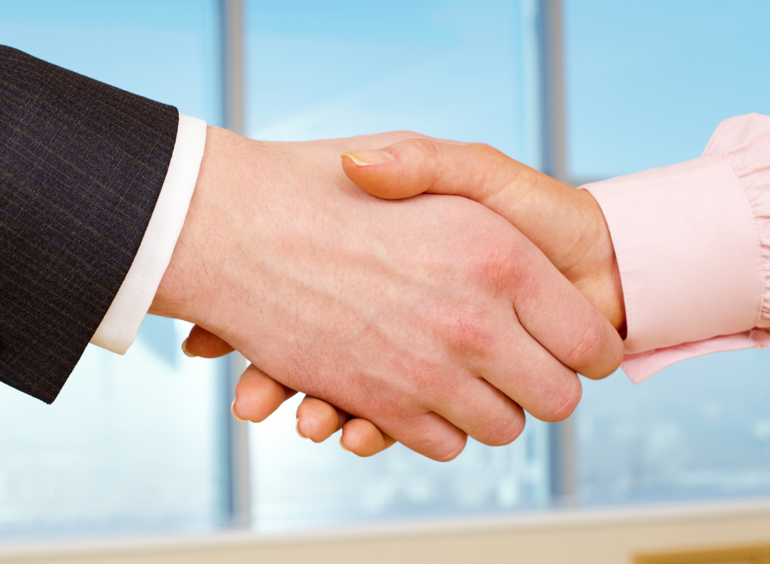 A man and a woman are shaking hands in front of a window