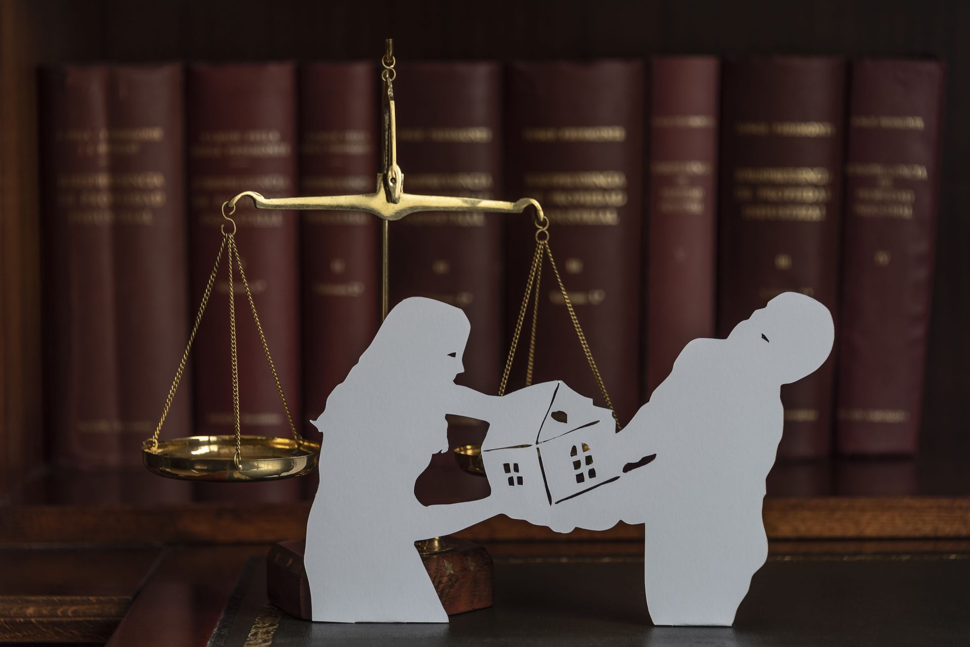 Silhouettes exchanging a house in front of law books and scales of justice