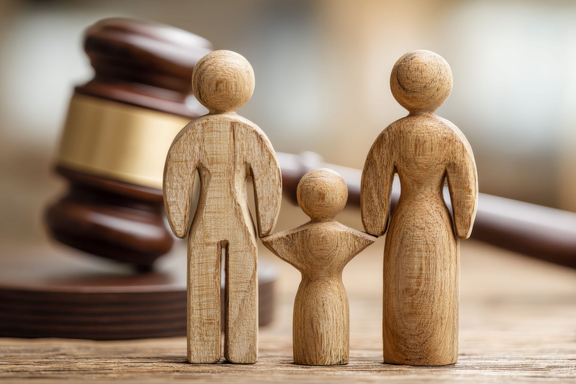 Wooden family figurines in front of a judge’s gavel, symbolizing family law or custody