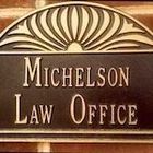 Micheson Law Office sign, gold lettering on a brown background, above a brick wall.
