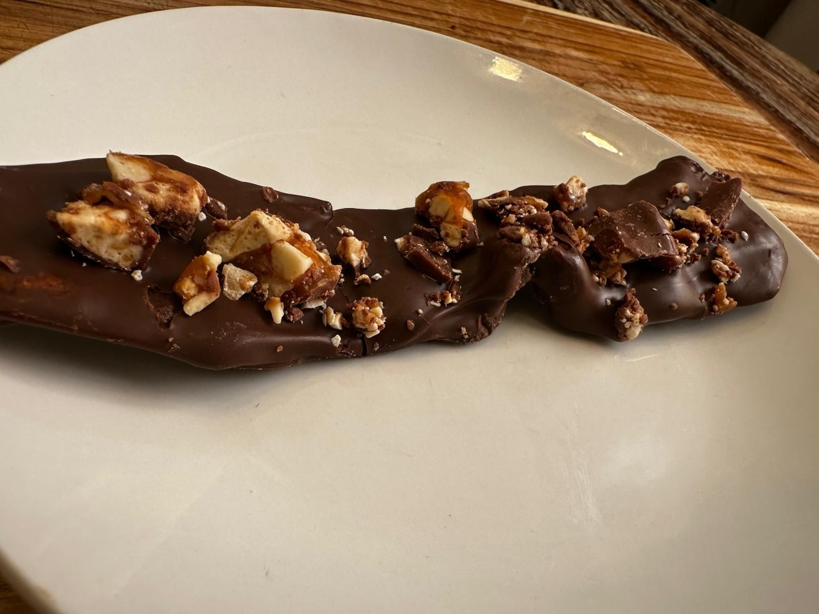 Dark chocolate bark with chopped nuts on a white plate.