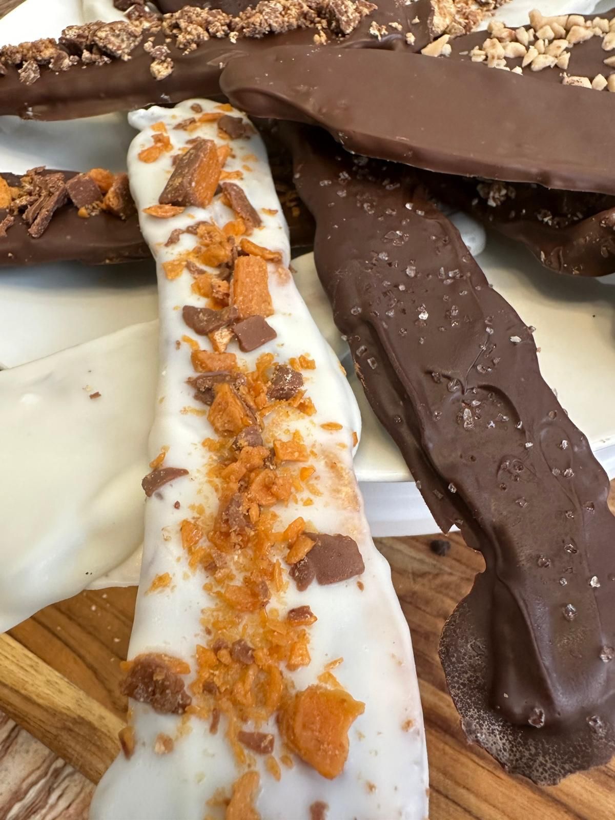 Chocolate-covered toffee bark, some with white chocolate and toffee bits, others with dark chocolate and nuts.