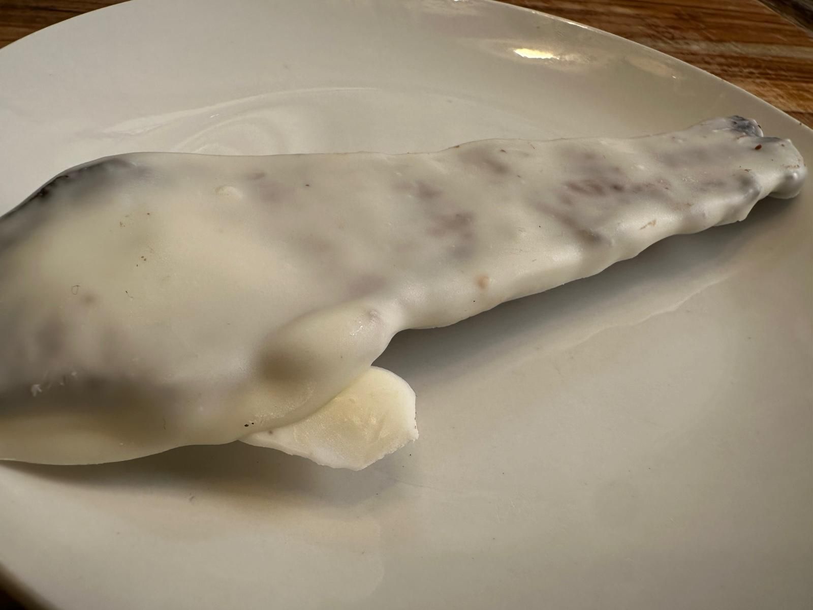 Fillet of fish covered in white sauce on a white plate.