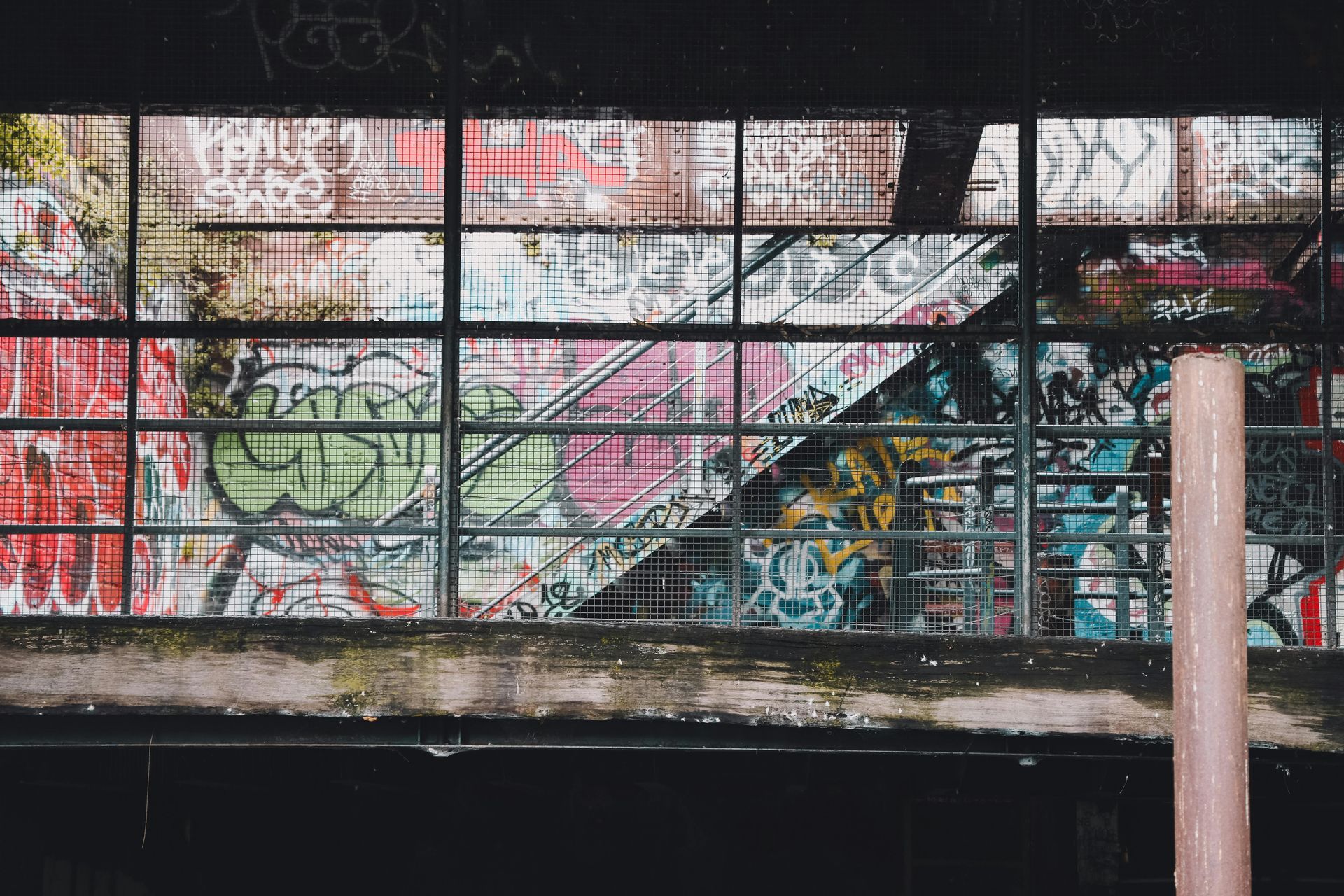Graffiti-covered window with metal bars; vibrant colors.