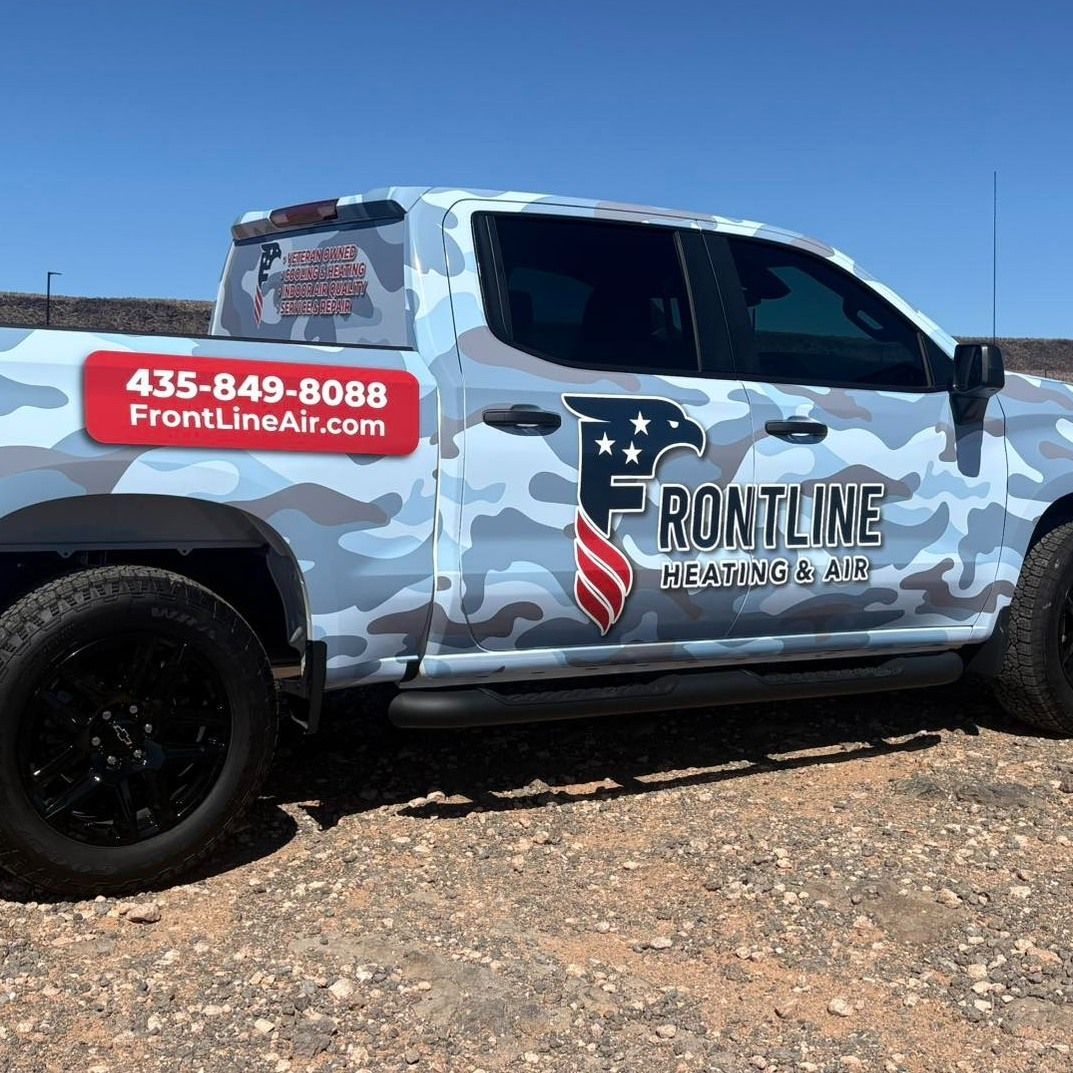 Camouflage pickup truck with FrontLine Air logo and phone number parked on rocky ground under a clear sky